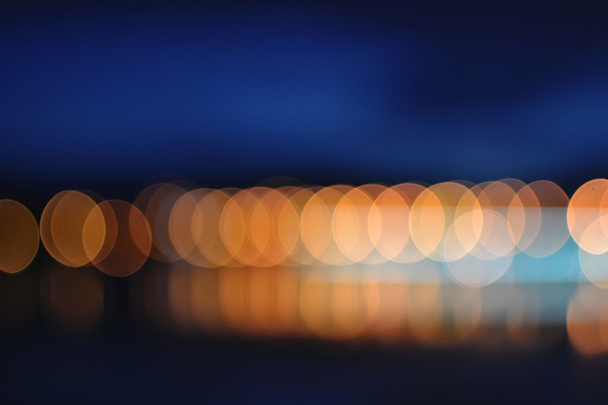 Abstract bokeh of colorful lights reflecting in the night sky, creating a serene scene.