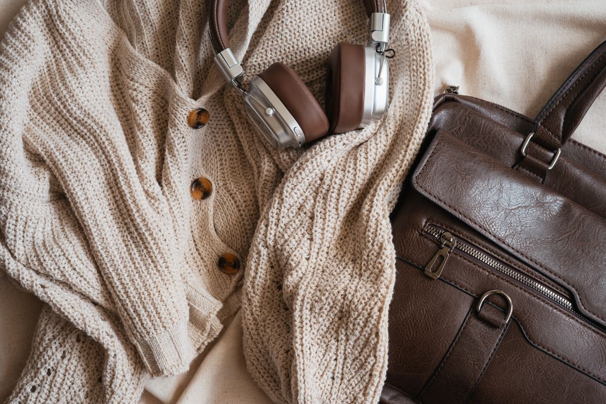 Warm fashion flat lay with knit cardigan, headphones, and leather bag.