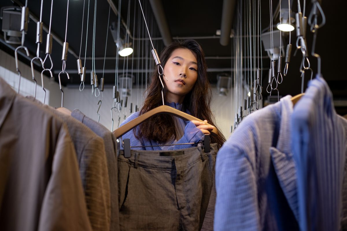 Asian woman browsing clothes in a trendy fashion boutique indoors.