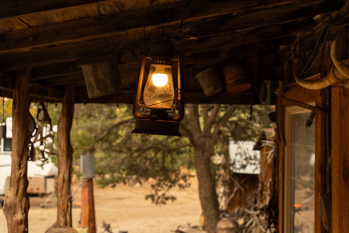 A glowing lantern hangs from a rustic wooden porch, evoking the ambiance of the wild west.