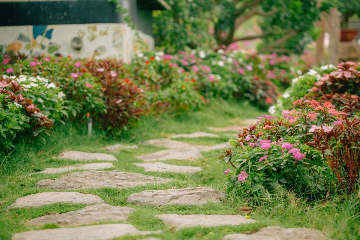 A serene garden path lined with colorful flowers creates a tranquil outdoor setting.