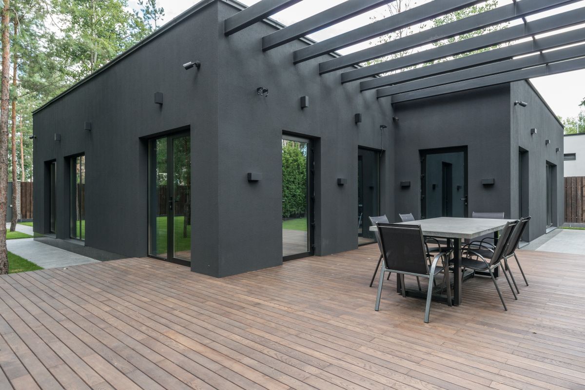 Contemporary black house with spacious wooden terrace and outdoor seating area.