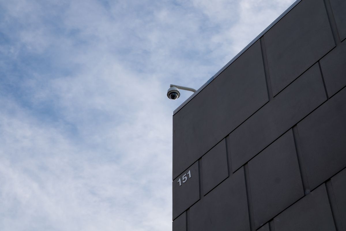 A modern building facade with a security camera against a cloudy sky in Fort Worth, TX.