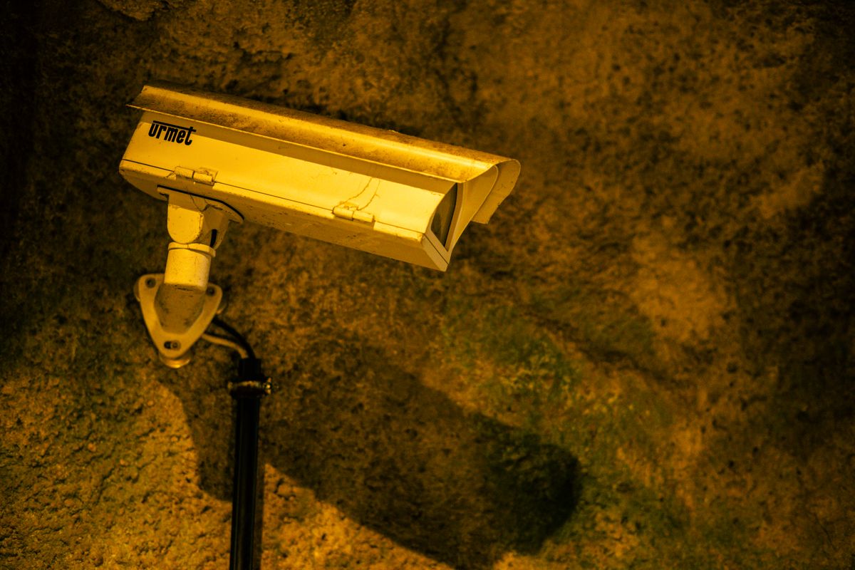 Close-up of a security camera mounted on a textured wall at night.