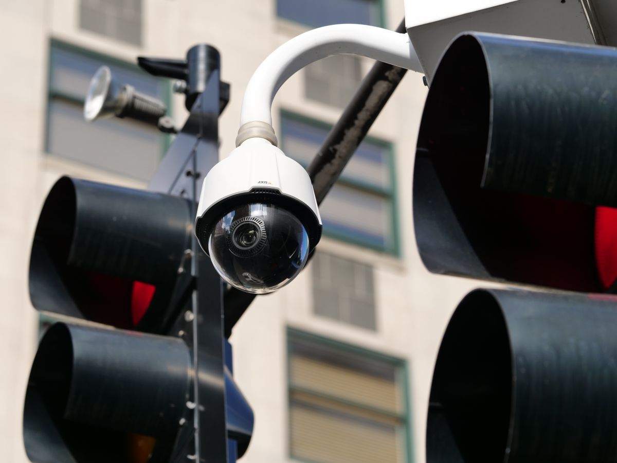 Close-up of a modern dome security camera monitoring an urban street.