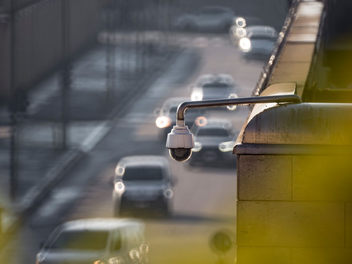 A security camera monitoring activity on a bustling city street with multiple cars in the background.