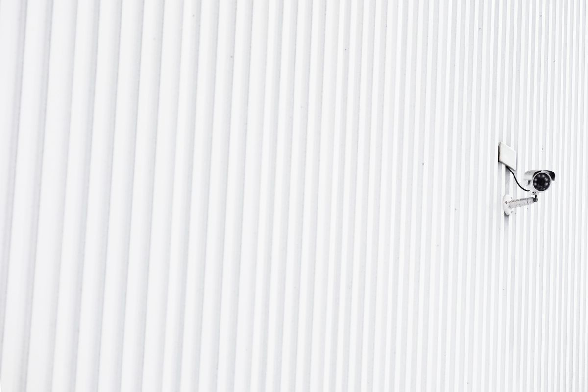 A minimalist photo of a security camera mounted on a corrugated wall, emphasizing privacy.