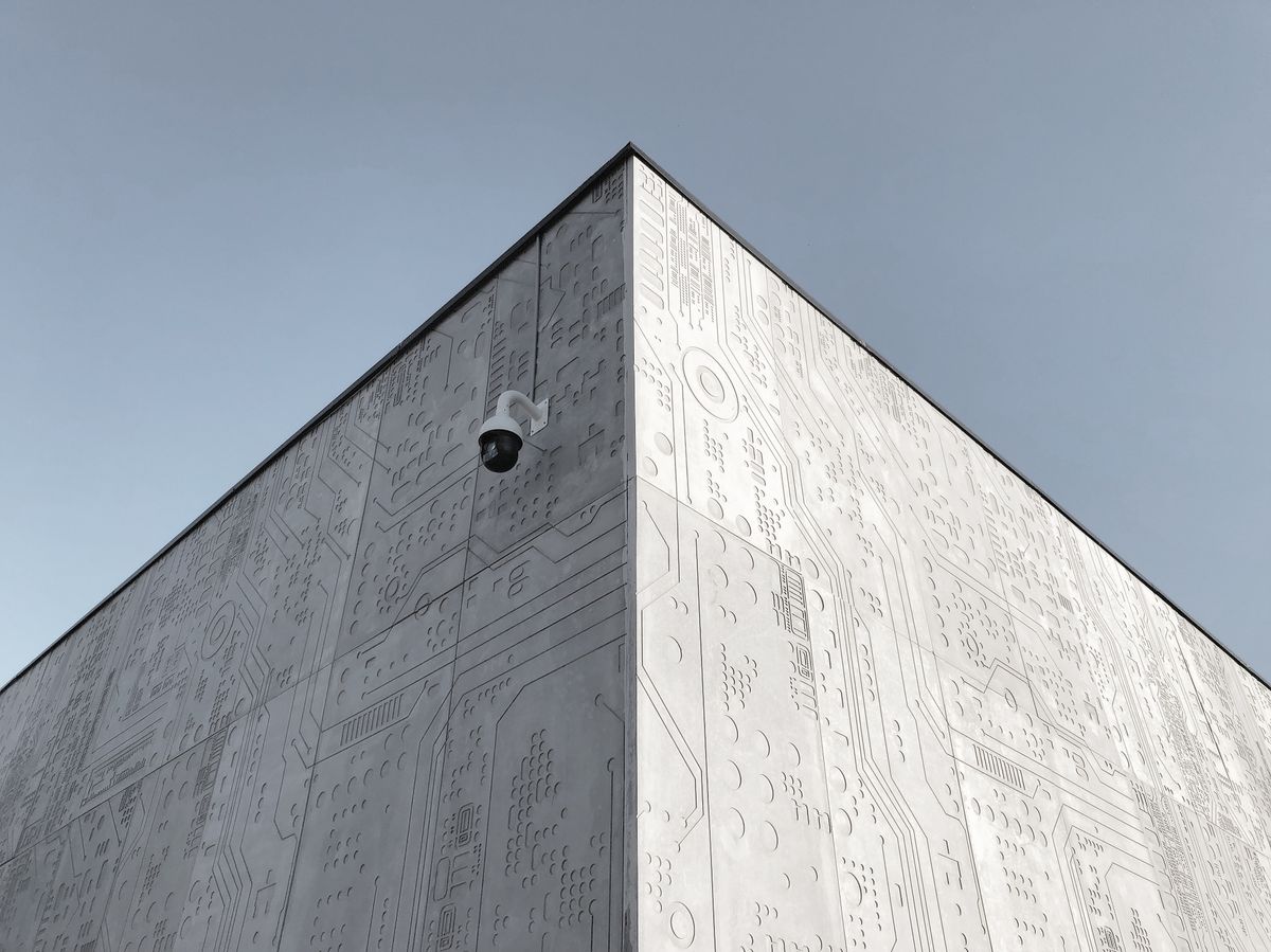 Elevated view of a futuristic building corner in Moscow, featuring circuit design patterns and a security camera.