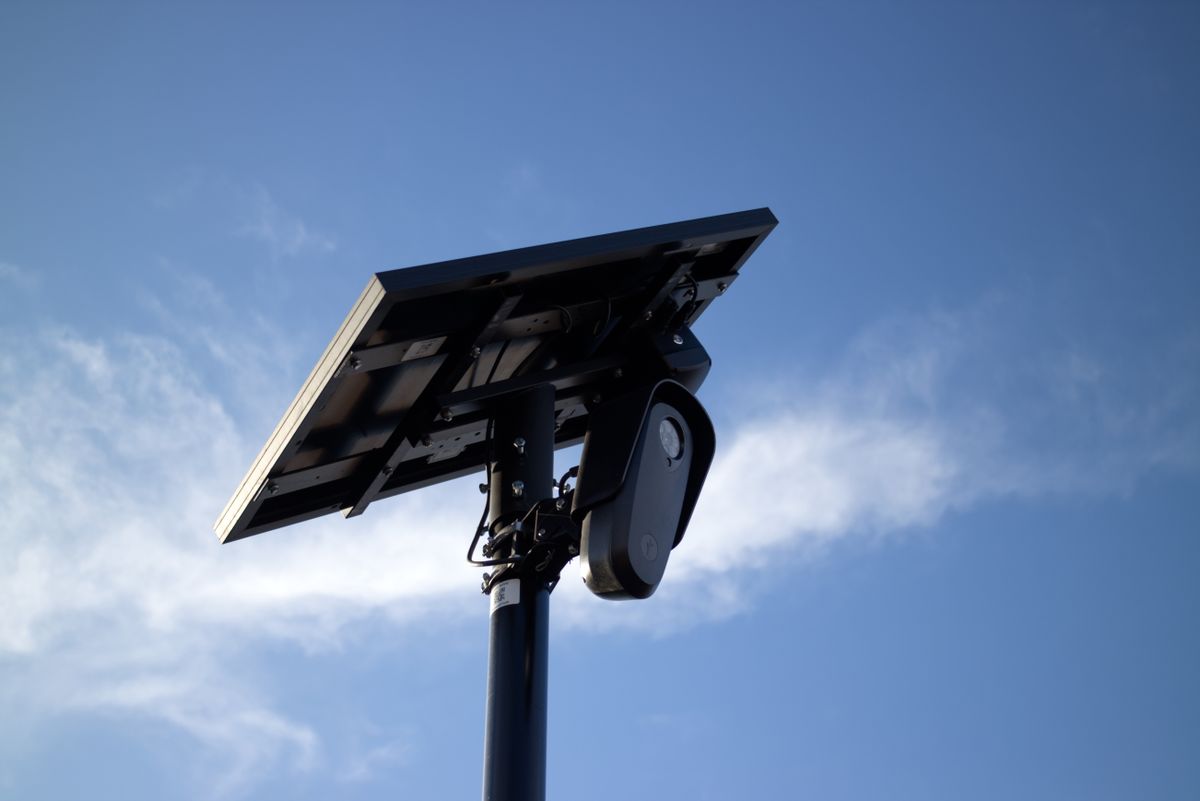 Solar-powered CCTV camera mounted on pole with bright sky background, symbolizing security and technology.