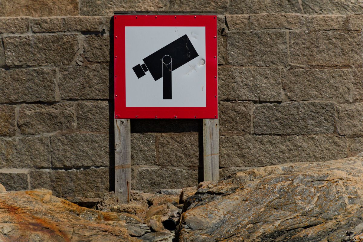 A bold CCTV warning sign on a rugged stone wall, emphasizing security and surveillance.