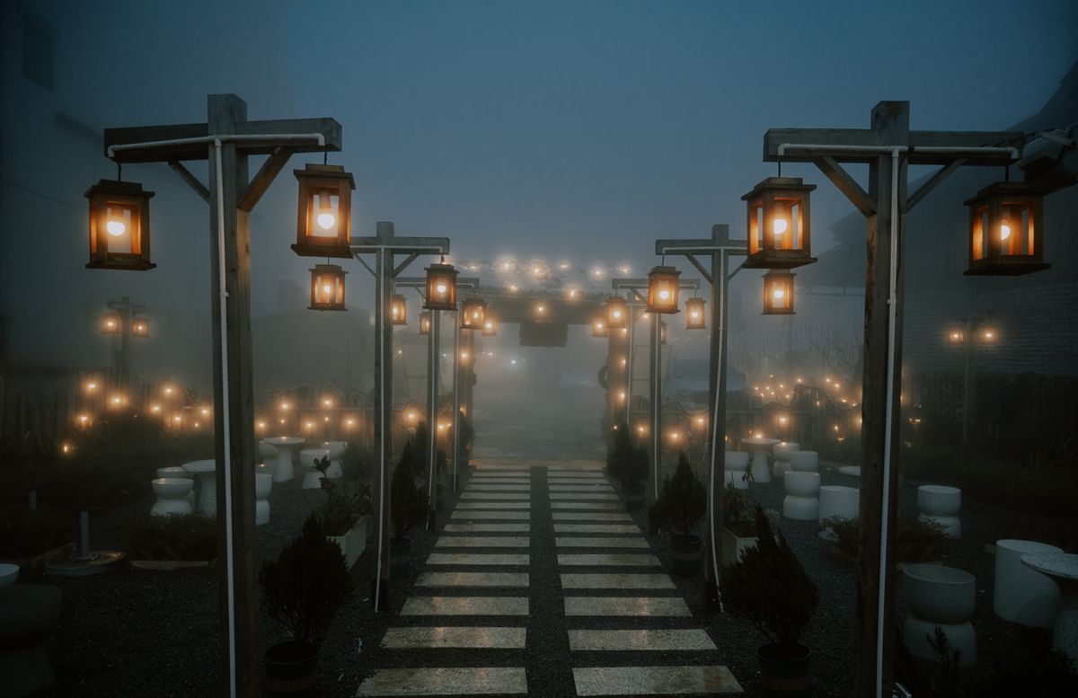 Enchanting misty pathway illuminated by lanterns at night, creating a serene and mystical atmosphere.