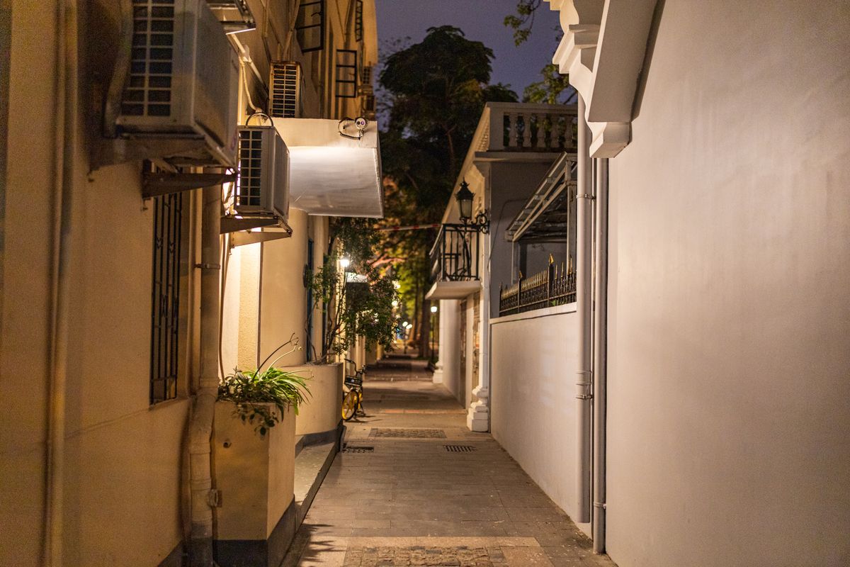 A peaceful night view of a narrow residential alleyway in Guangzhou, China, featuring air conditioners and soft lighting.
