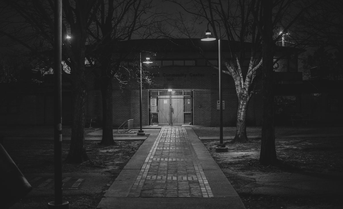 A dark, atmospheric alleyway at night in Houston, Texas. Monochrome street lights enhance the scene.