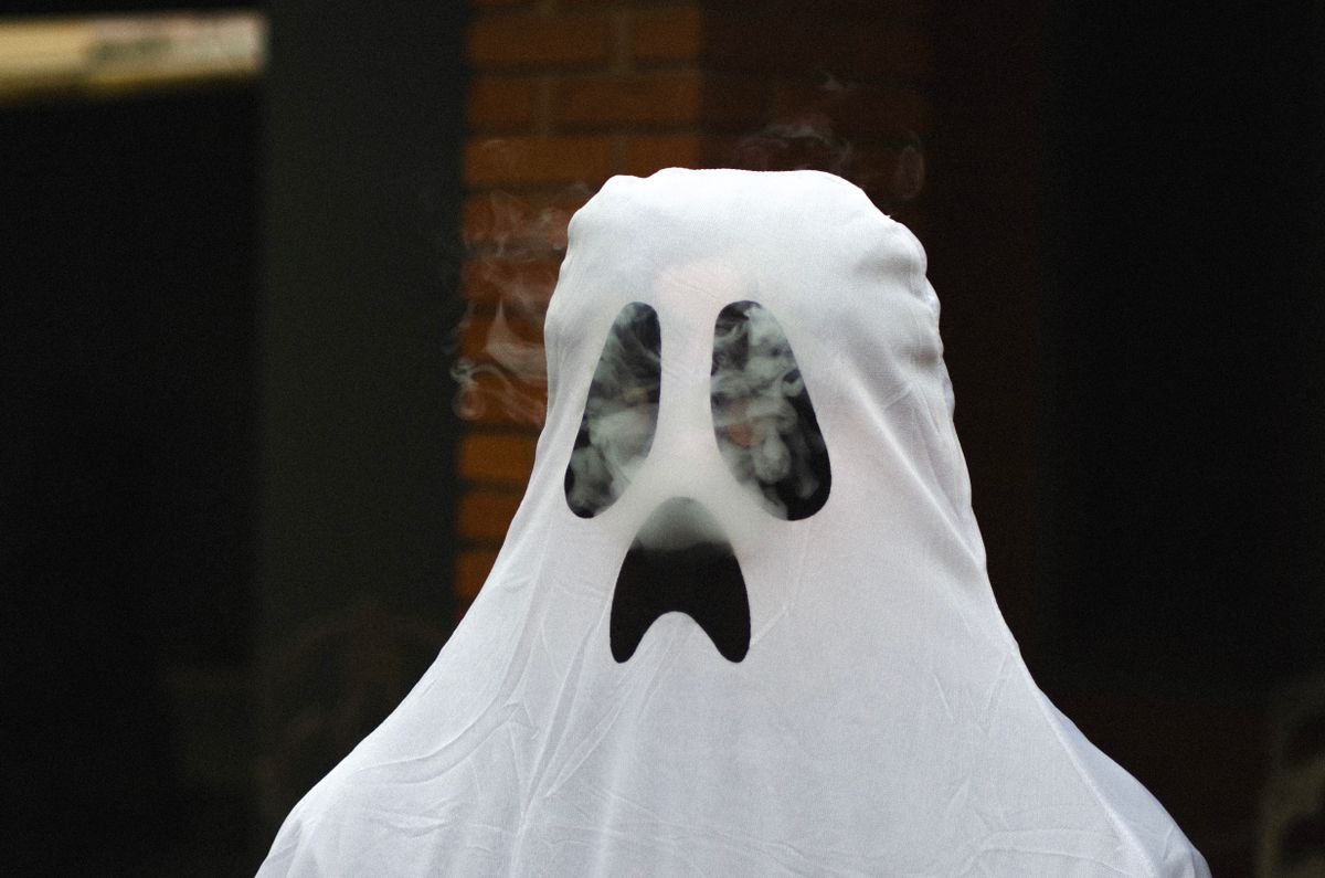 A spooky ghost costume with smoke effect for Halloween fun outdoors.