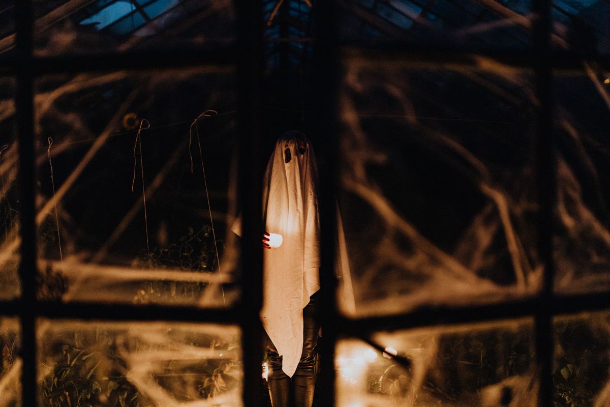 A ghostly figure stands in a dim room, creating a spooky Halloween ambiance.