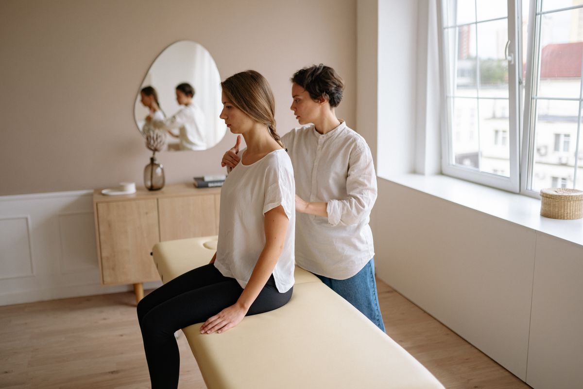 A massage therapist providing a relaxing shoulder massage to a woman in a peaceful spa environment.