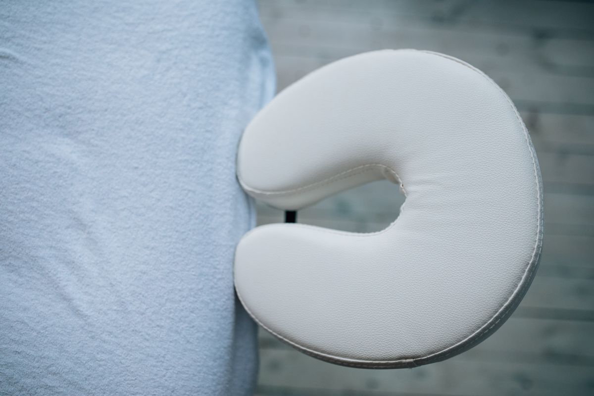 Minimalistic top view of a massage table with a white headrest cushion for relaxation.