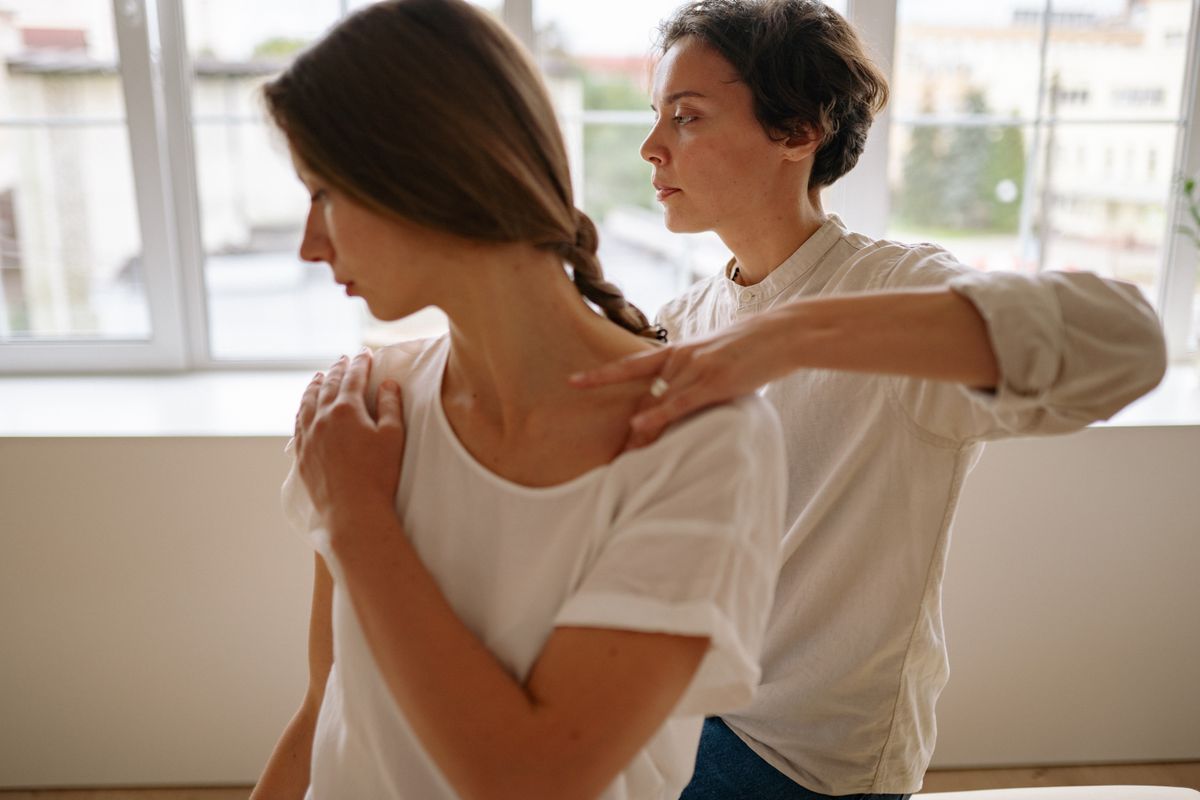 A massage therapist providing shoulder treatment to a client in a serene indoor setting.
