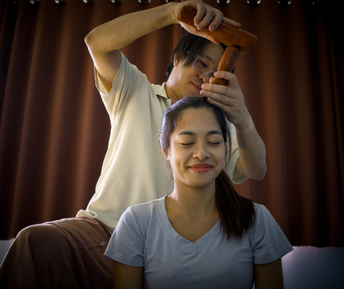 Holistic head massage technique using wooden tools for relaxation in Chiang Mai, Thailand.