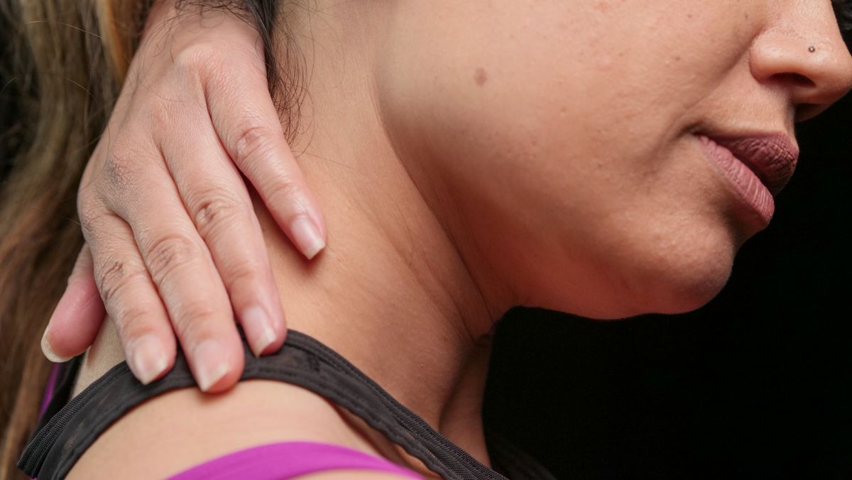 Close-up of a woman holding her neck, indicating pain or discomfort.