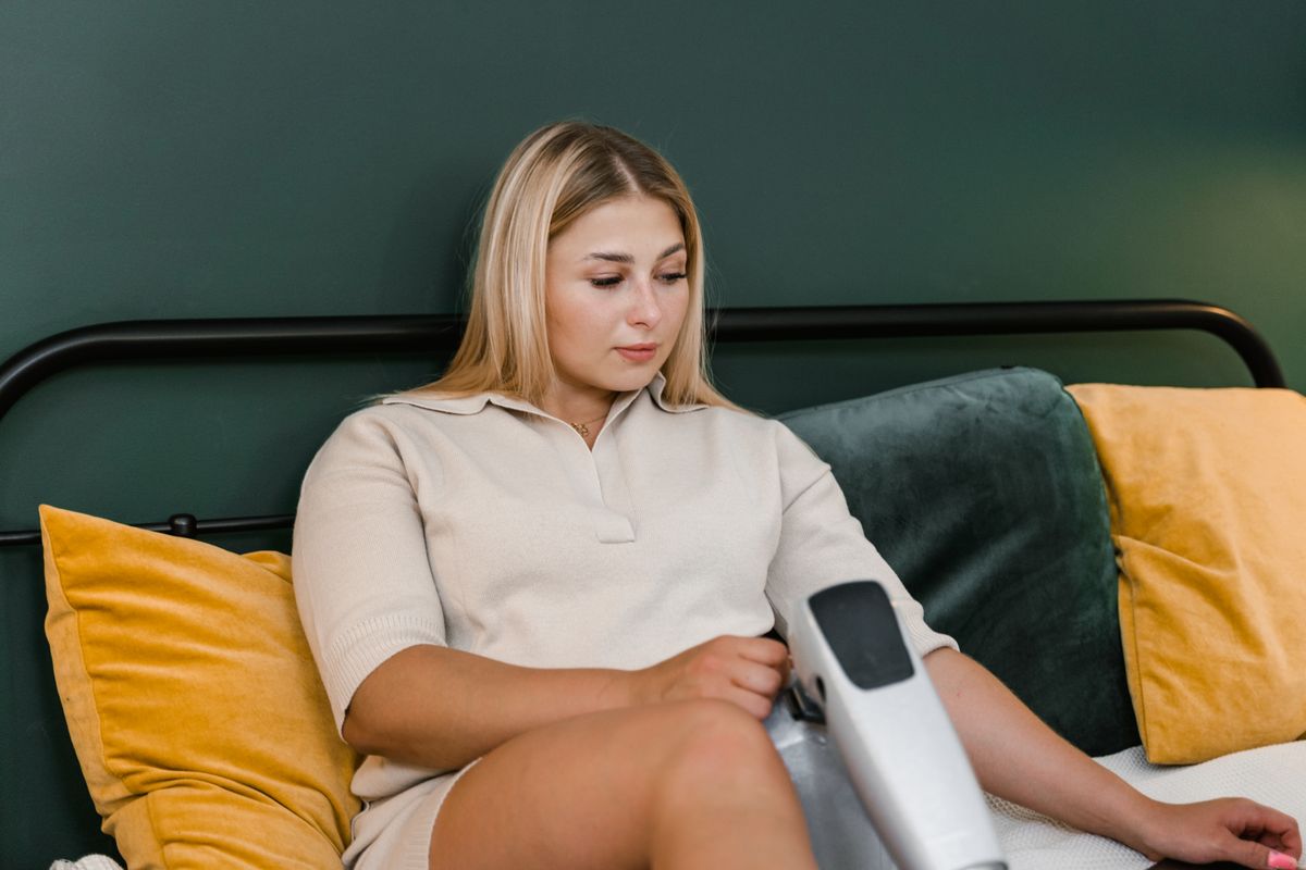 Woman sitting on bed using a device, embodying modern technology and comfort.