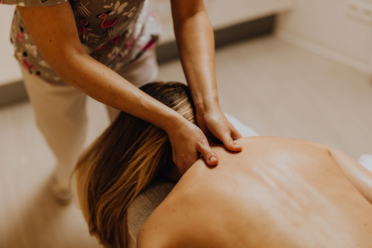 A professional masseuse performing a soothing back massage in a peaceful spa environment.