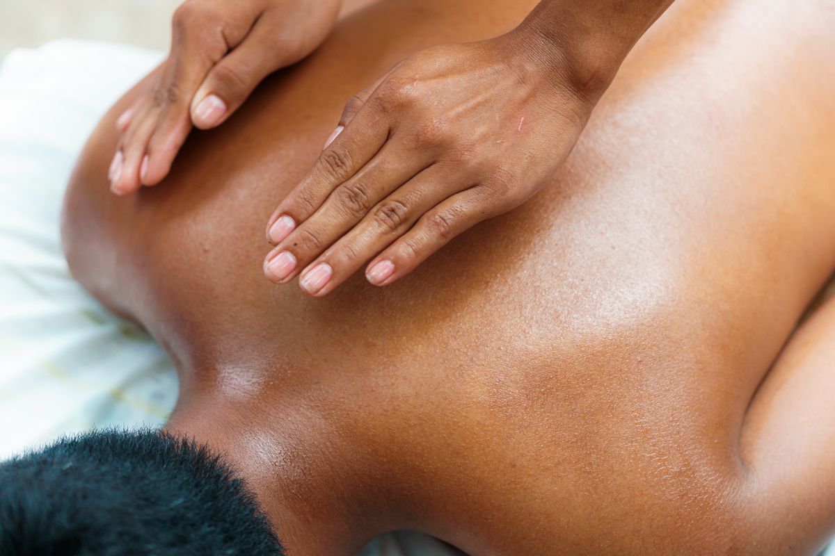 Hands giving a relaxing massage to a person lying on a massage table, promoting wellness.