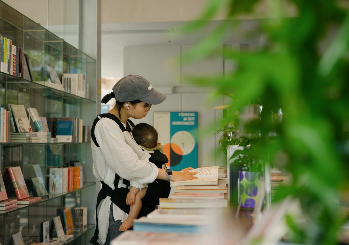 A mother with her baby in a library reading books. Warm indoor ambiance.