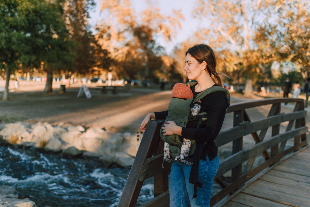 A serene moment of a mother and baby on a wooden bridge in an autumn park.