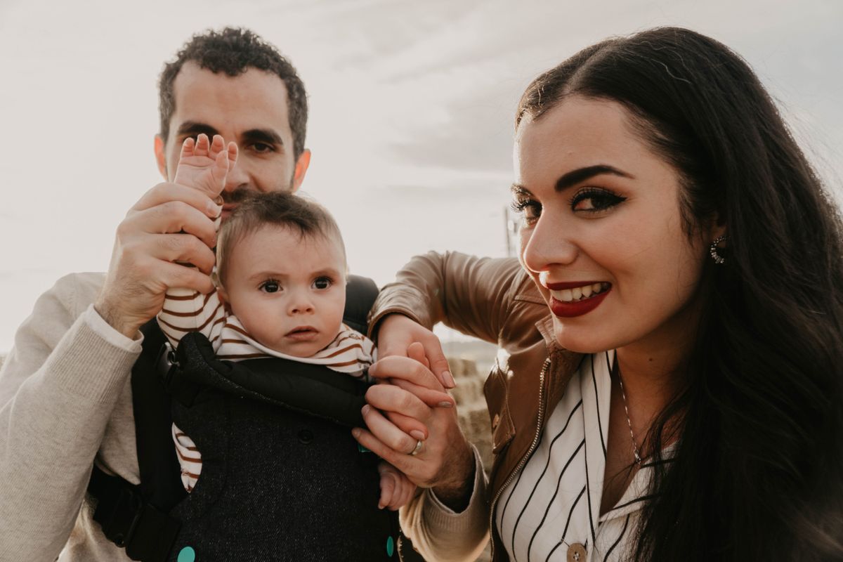 Loving family enjoying time together outdoors with their baby in a carrier.