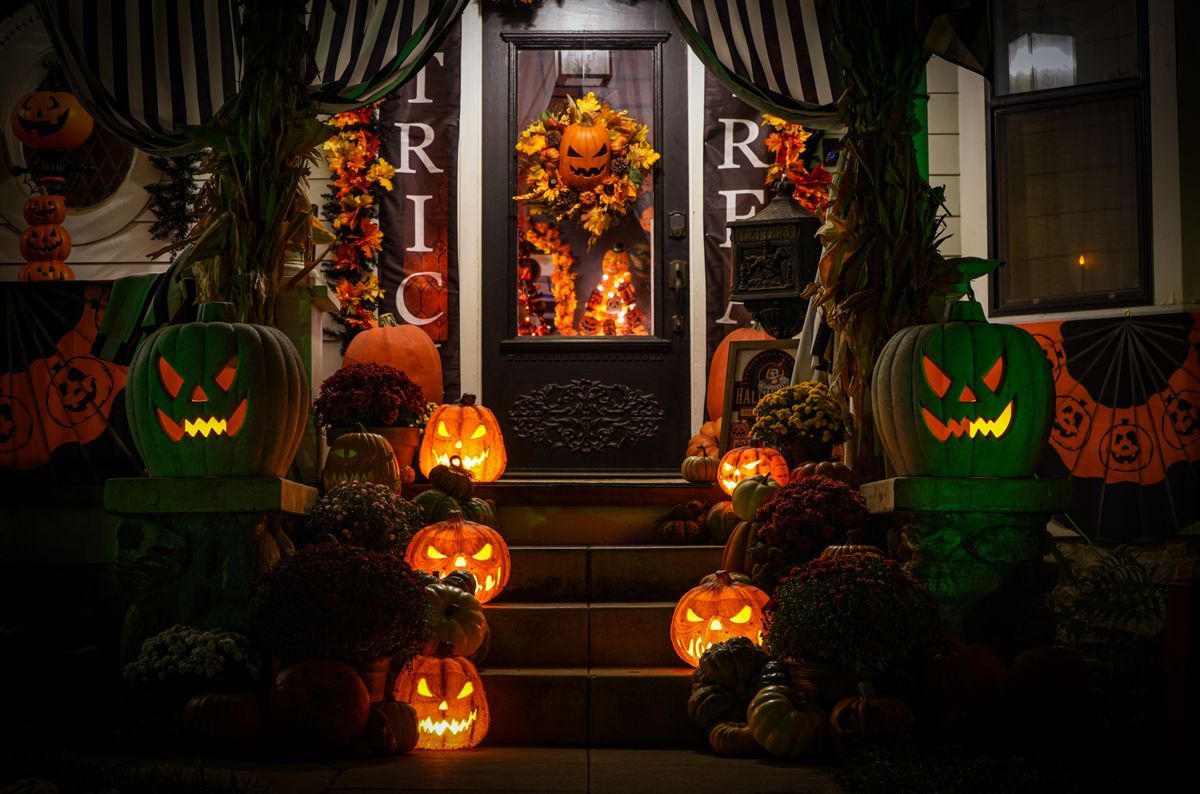 Decorated porch with glowing jack-o'-lanterns on Halloween night.