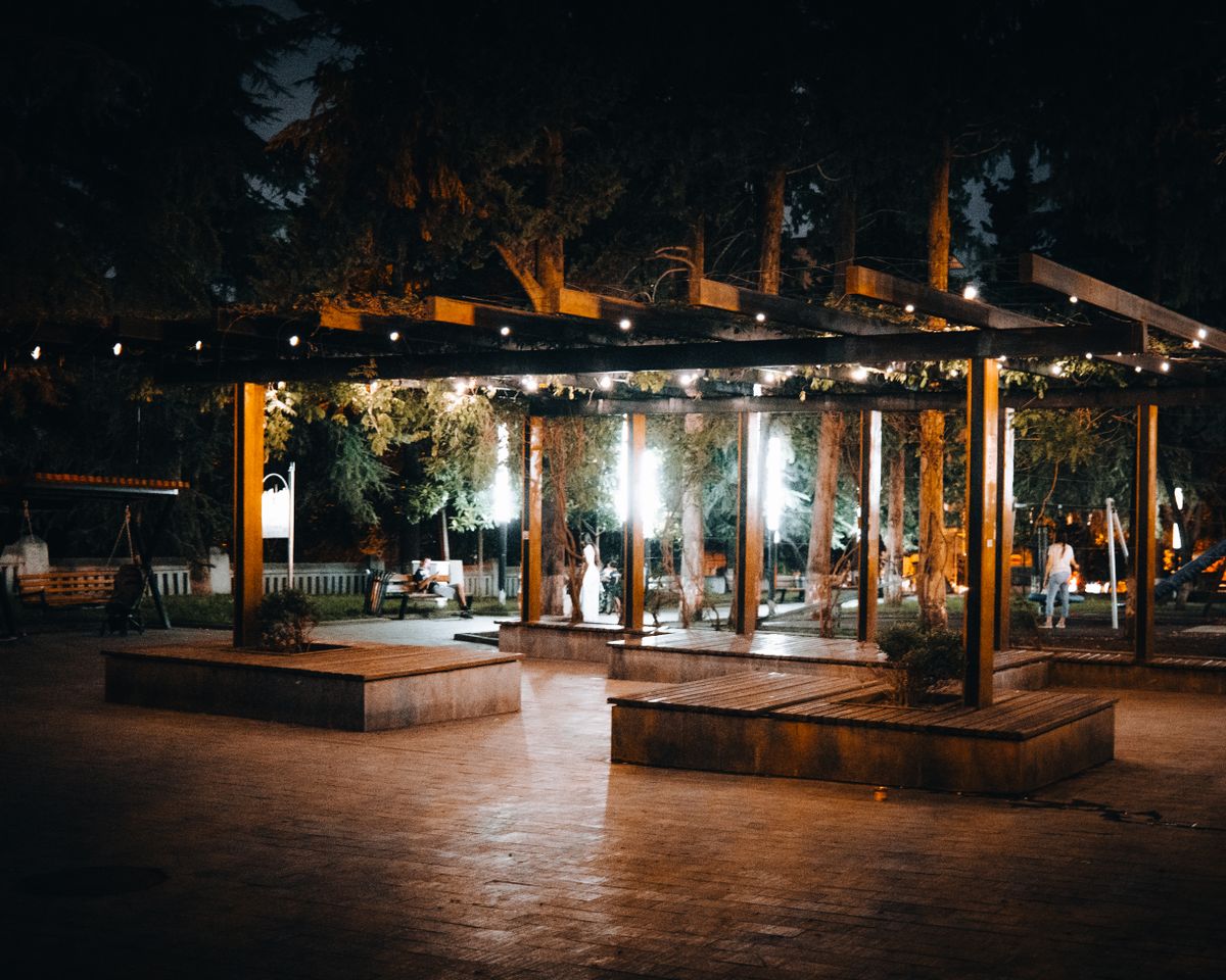 A beautifully lit outdoor pavilion at night with ambient lights and lush surroundings.