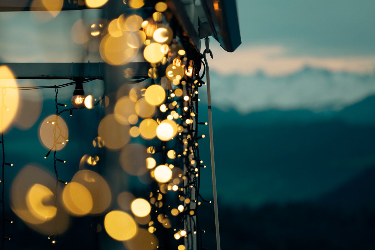 Bokeh effect with string lights and a serene mountain backdrop at dusk.