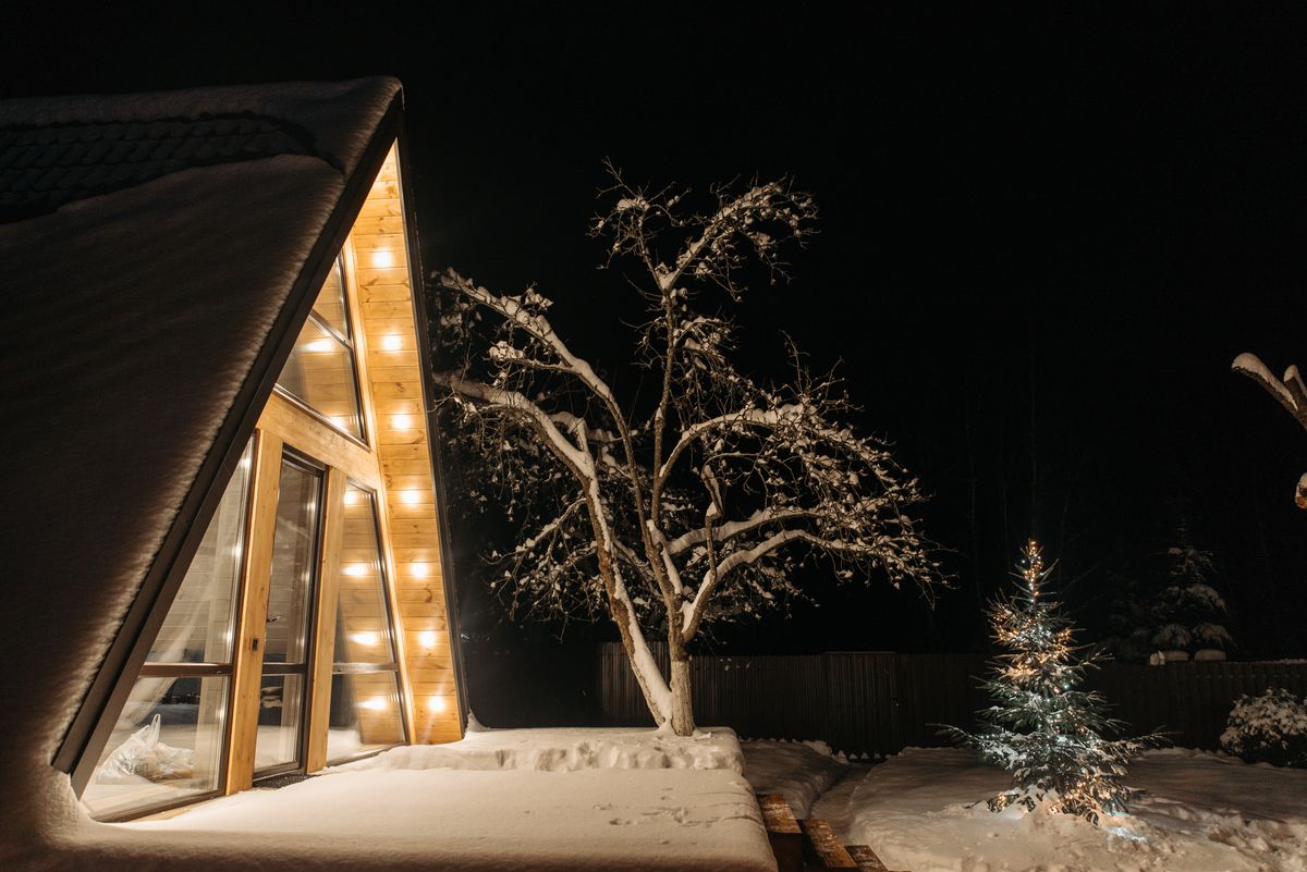 A beautifully lit cabin in a serene snowy landscape under the starry night sky, perfect for winter getaways.
