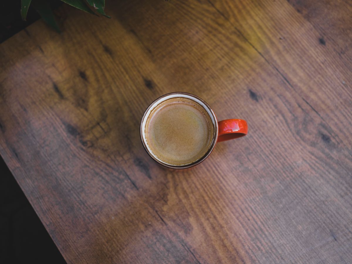 Red coffee mug with steaming espresso on a rustic wooden table. Perfect for cozy lifestyle or morning beverage themes.