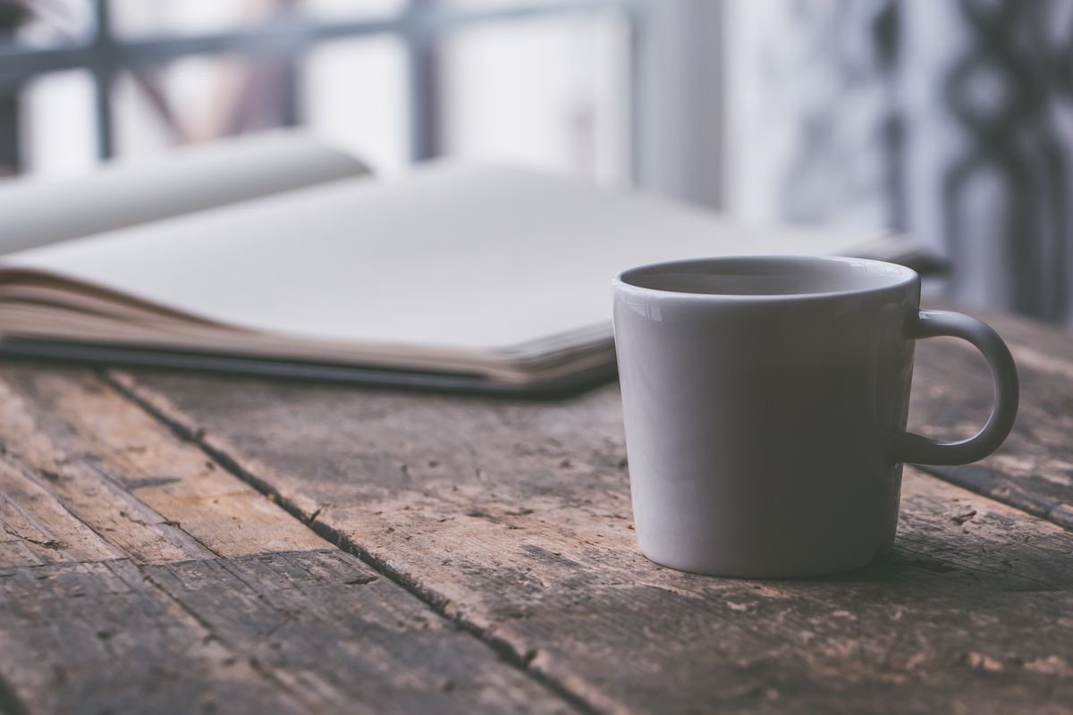 A mug of coffee on a rustic wooden table, perfect for a cozy moment or reading session.