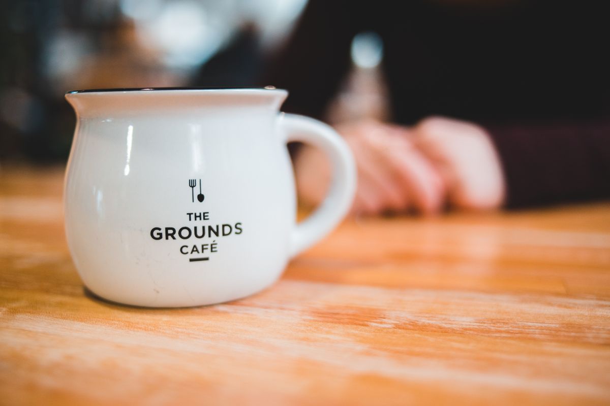 Close-up of a coffee mug on a wooden table in a cozy café setting.
