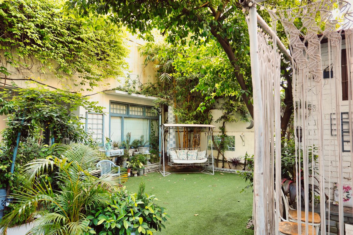 Lush backyard garden with a swing, surrounded by greenery and cozy seating.
