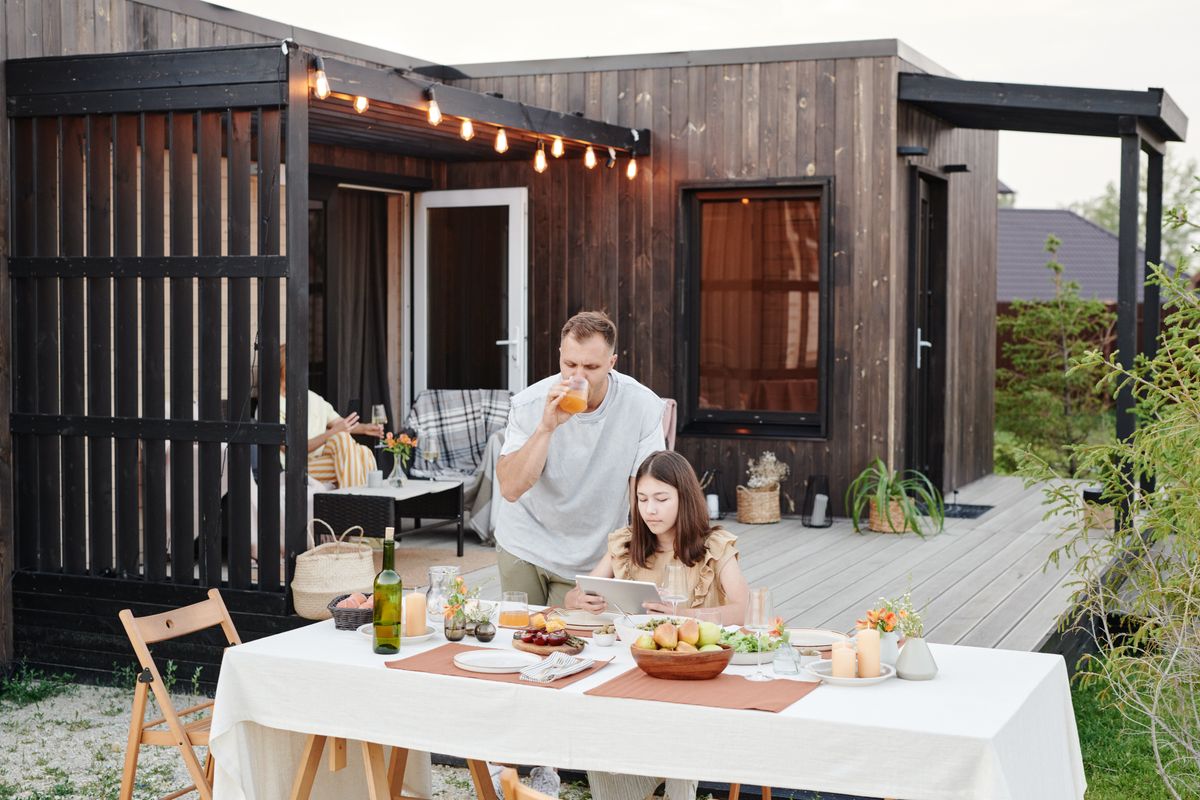 Couple enjoying an intimate evening meal outdoors on a stylish wooden deck with modern accents.
