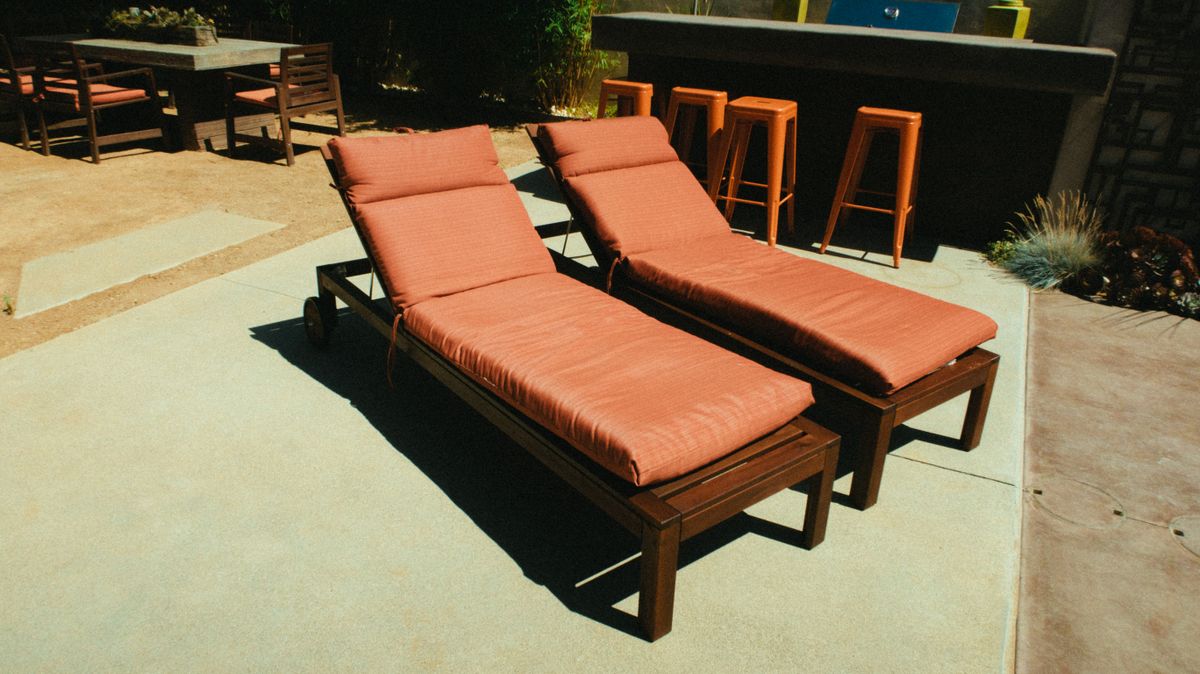 Stylish outdoor patio with modern wooden deck chairs and dining area.
