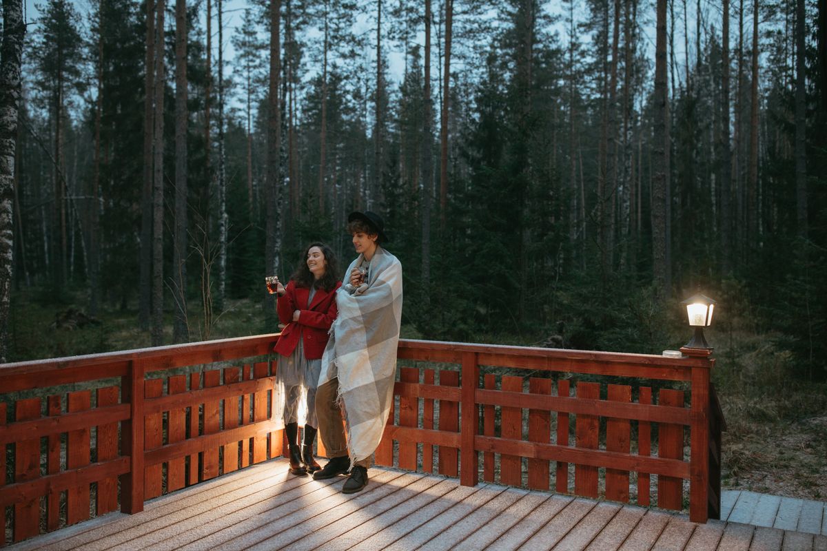 A couple relaxing on a cozy wooden deck in a forested area, enjoying a serene evening together.