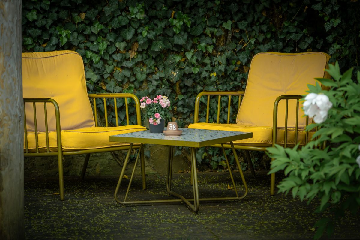 Yellow chairs and table in a lush outdoor setting in Lemgo, Germany. Perfect for summer relaxation.