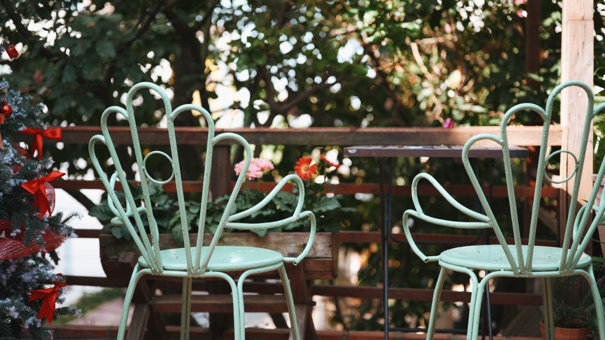 Outdoor garden scene with vintage metal chairs and festive decorations.