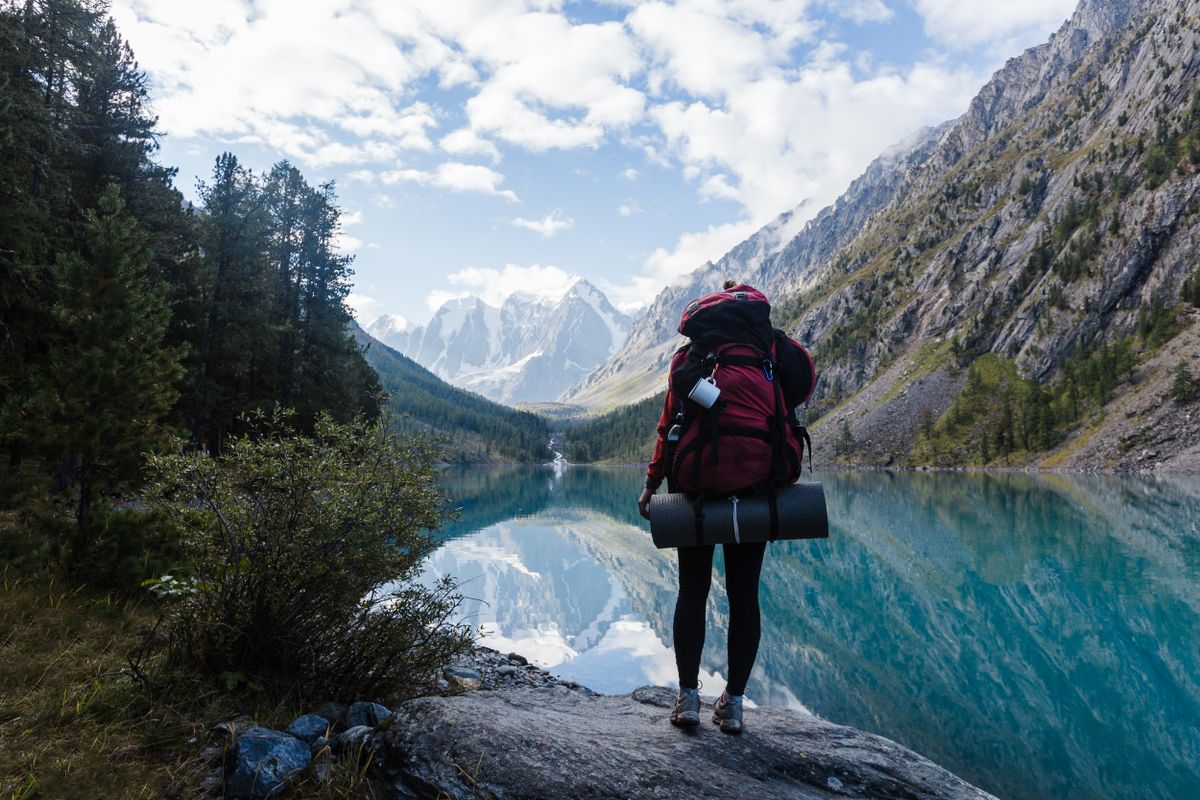 Backpacker enjoys serene mountain lake view in Altai Republic, Russia. Perfect for adventure and nature enthusiasts.