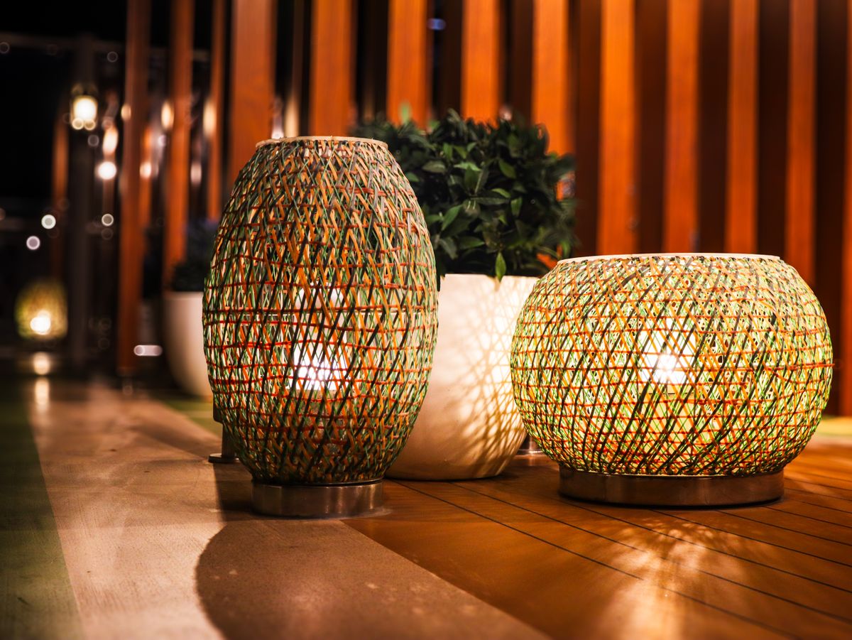Elegant outdoor lighting setup with woven lanterns casting warm glows on a wooden patio.