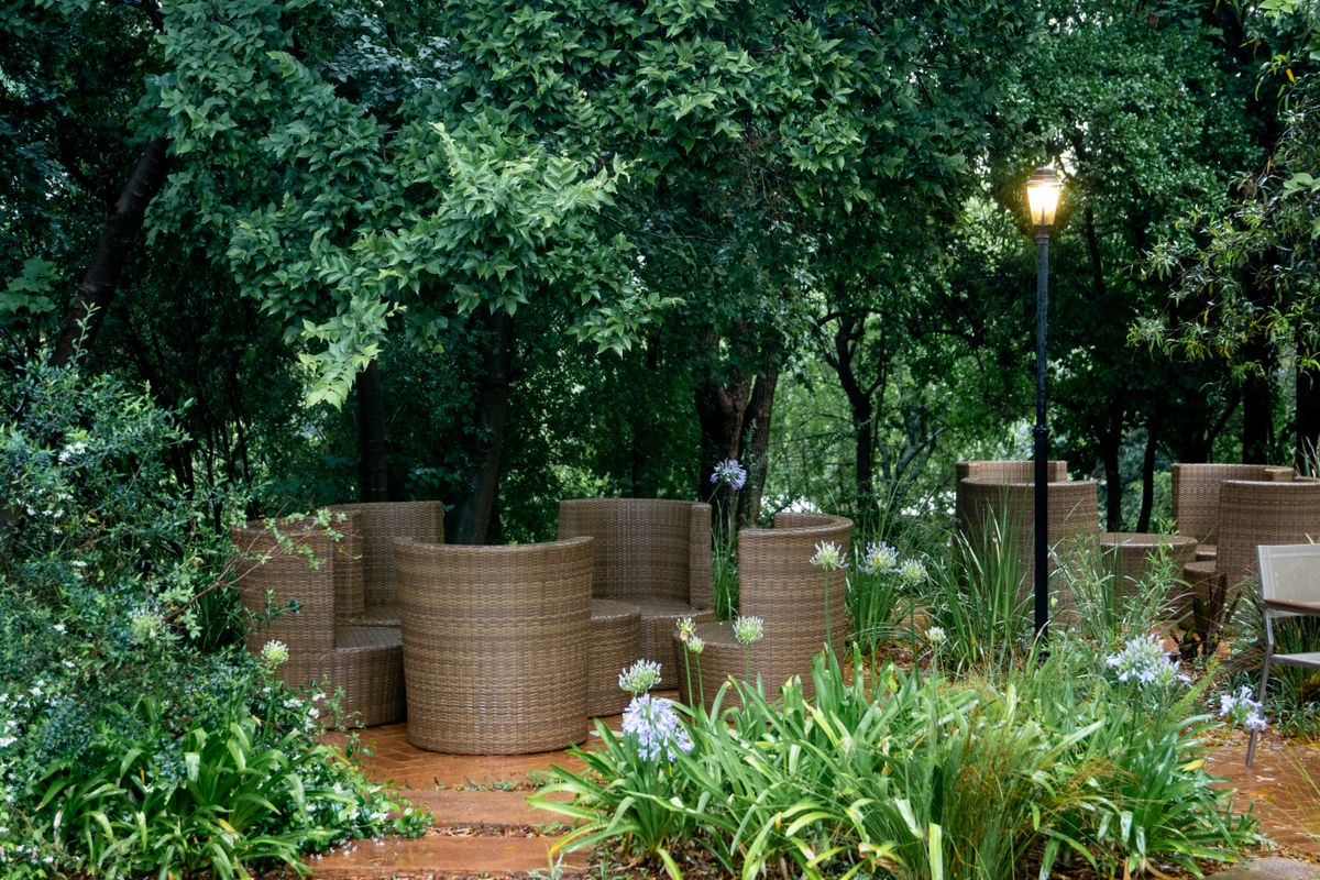 Elegant outdoor wicker seating surrounded by lush green foliage for a tranquil garden retreat.