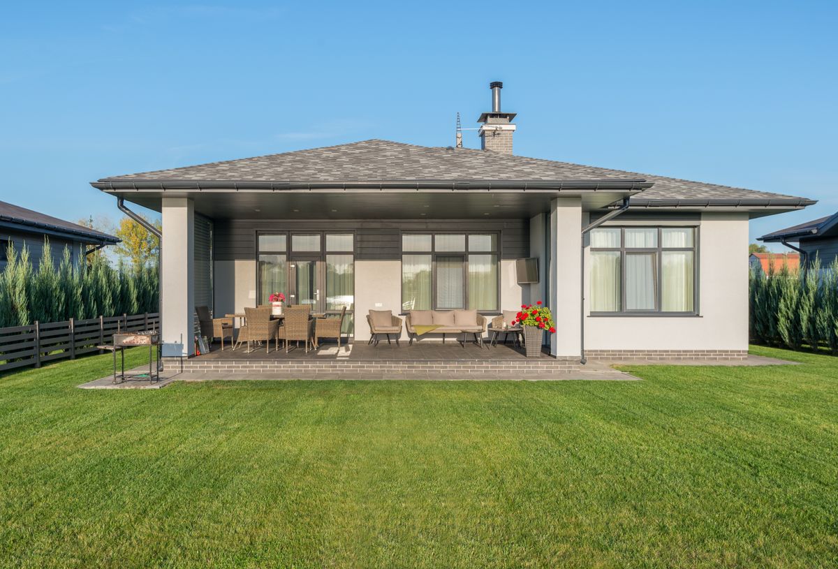 Contemporary house exterior with a large backyard patio and manicured lawn.