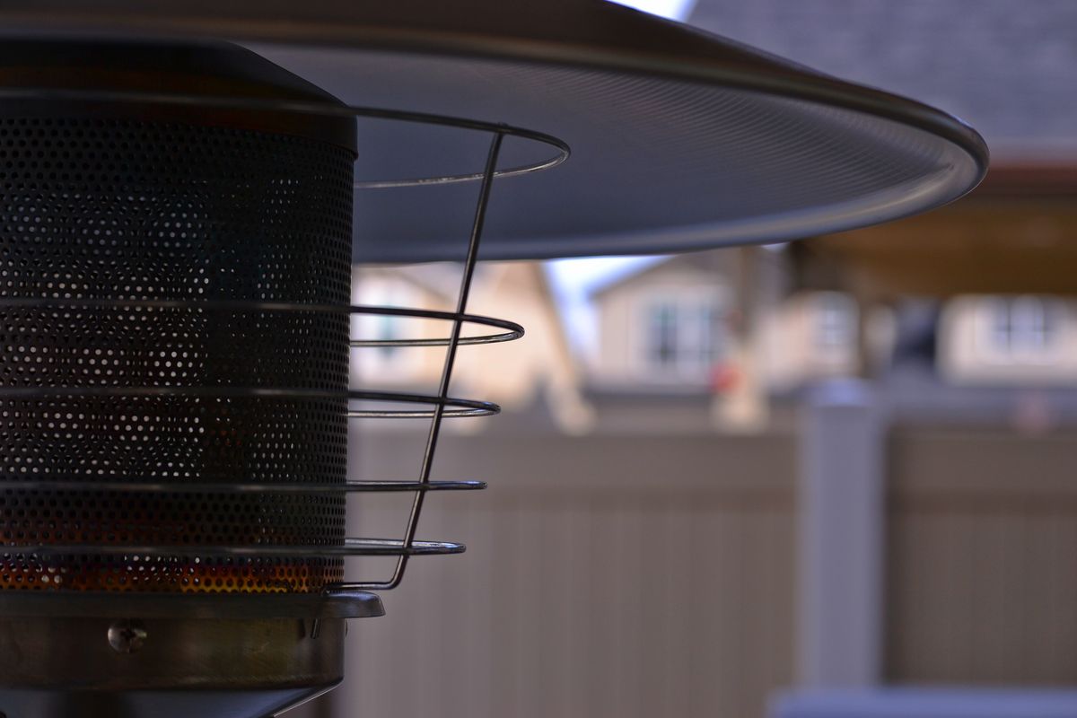 Detailed view of a modern outdoor patio heater with blurred suburban background, perfect for outdoor comfort concepts.