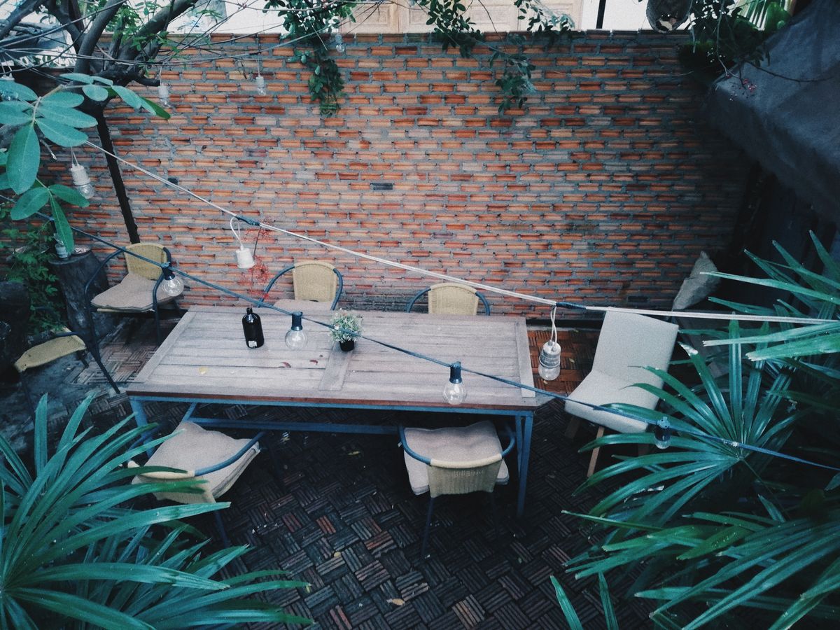 Cozy outdoor patio with wooden table and chairs against a rustic brick wall.