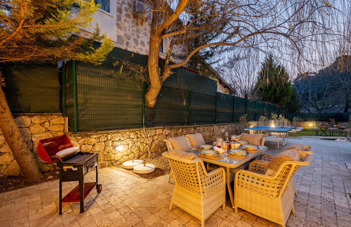 Inviting outdoor patio setup with dining table and barbecue grill at dusk.